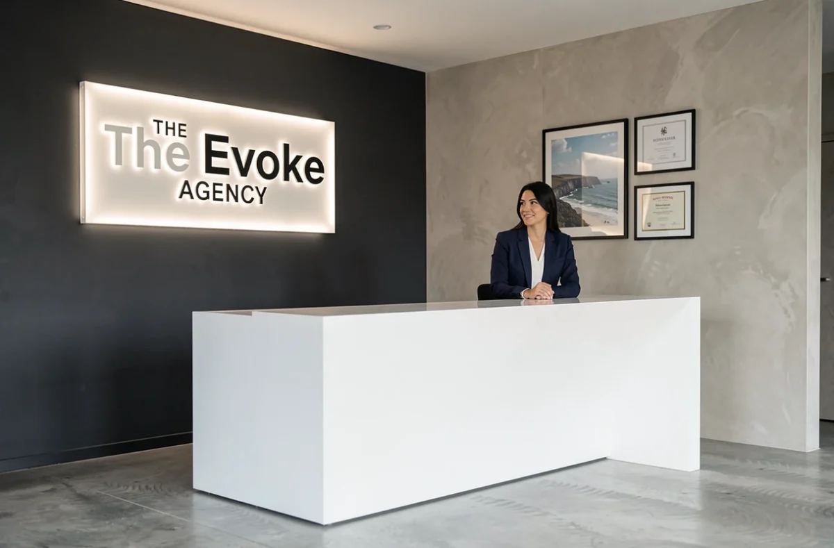 Réception moderne de l'agence The Evoke Agency avec une professionnelle en blazer marine devant un logo rétroéclairé